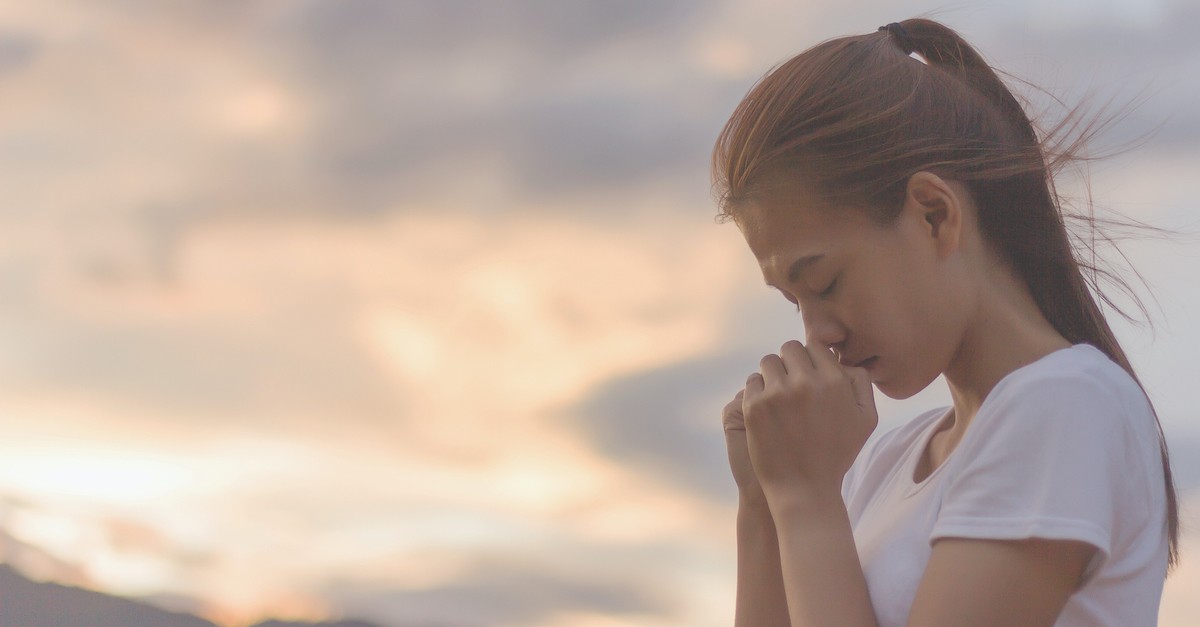 woman praying against sunset