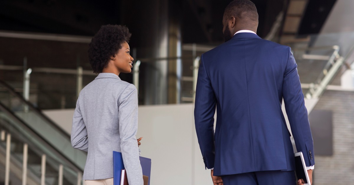 business man and woman walking through work building